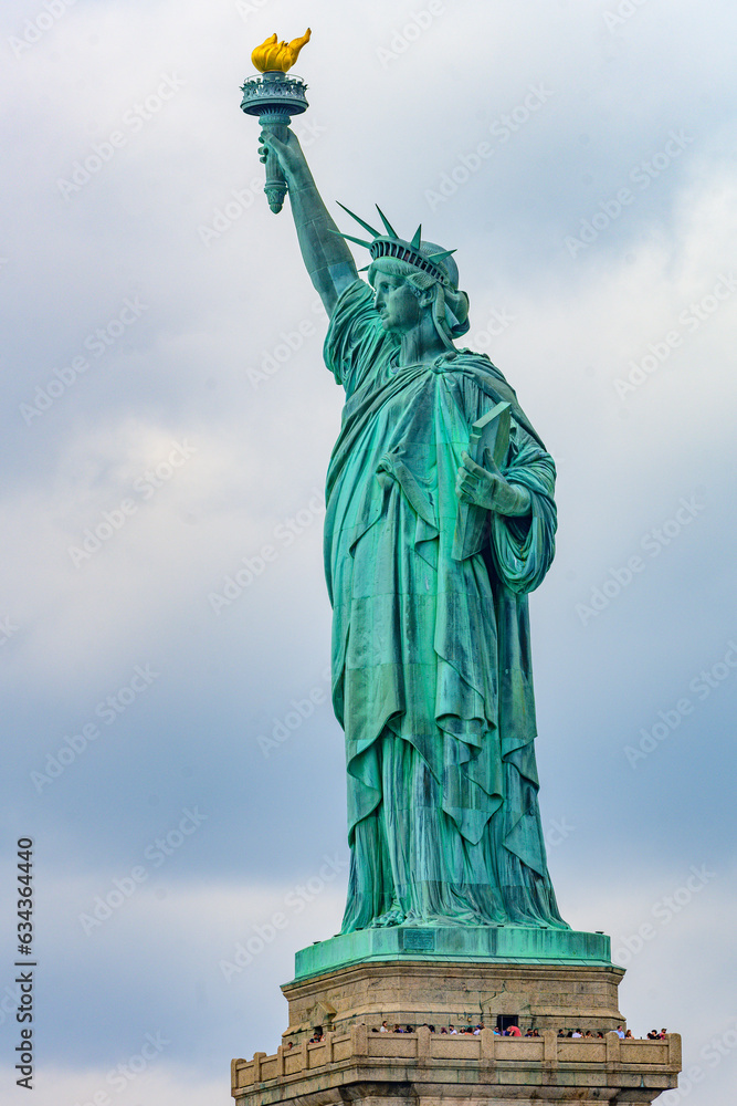 Obraz premium New York, New York, United States. August 07, 2023. Dramatic and detailed image of the Statue of Liberty with strong shades of green, sky with many clouds and very high resolution.