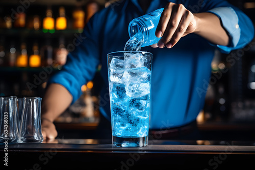 Bartender pouring a blue curacao cocktail into a chilled glass. photo