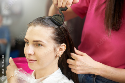 A woman does keratin hair strengthening in a beauty salon.