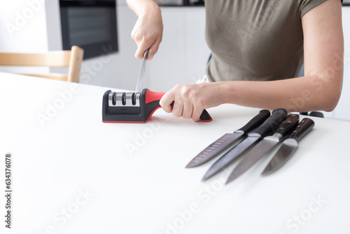 Close-up of woman sharpening knife with special knife sharpener at home 