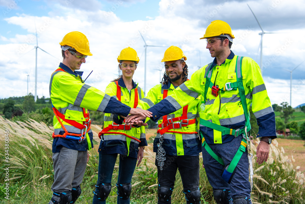 Wind turbine Engineer team working in wind turbine farm, join hands in unity Wind turbine Engineer team working in wind turbine farm, join hands in unity
