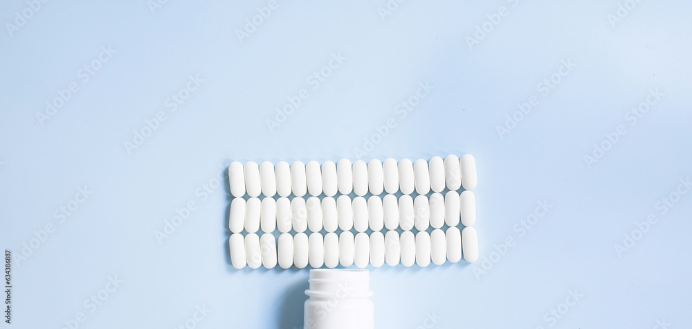 Lot of medicine pills on blue background. Scattered white pills on blue table. Lot of medicine pills on blue background. Scattered white pills on blue table.