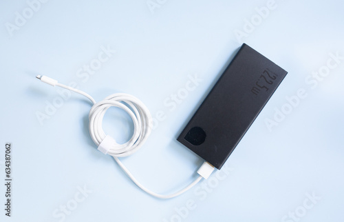 A smartphone charging with black power bank on blue background. Top view with copy space.