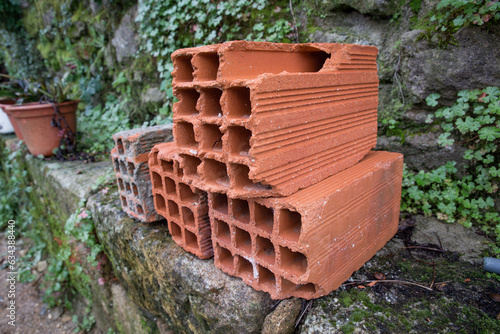 Detalhe de tijolos de 30x20x15 danificado e podre num muro de pedra.
