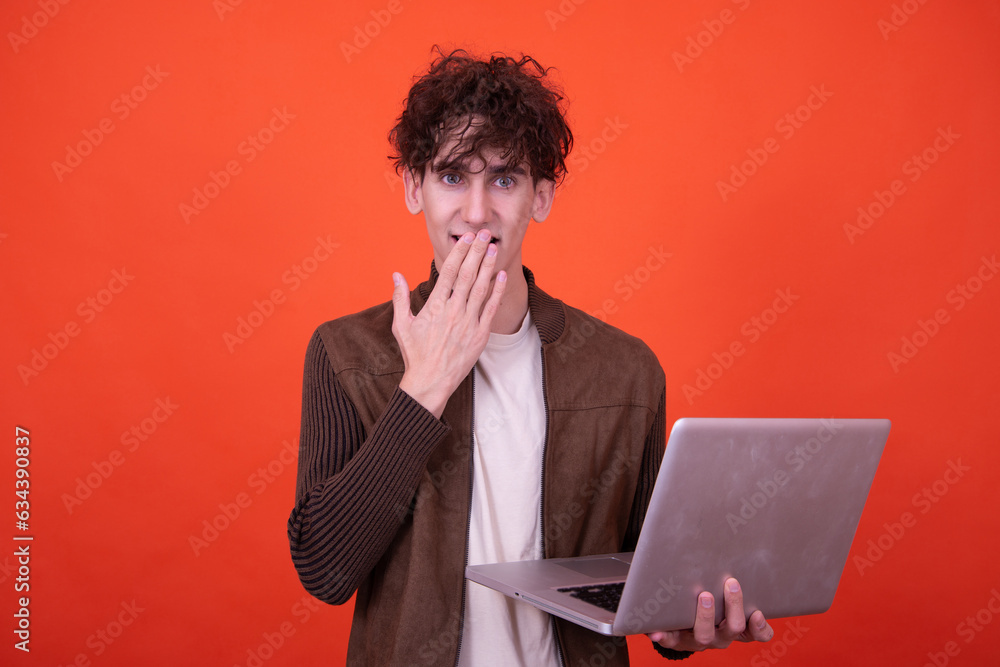 Funny curly guy posing on an orange background with a laptop. Funny curly guy posing on an orange background with a laptop.
