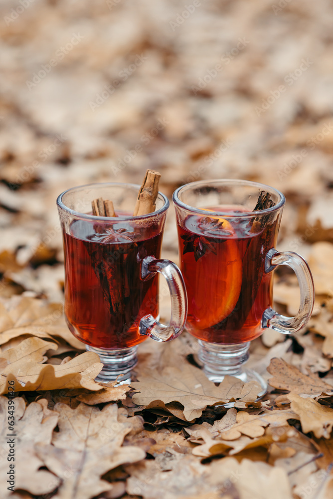 Two glasses of mulled wine on a wooden board against the background of a burning candle Two glasses of mulled wine on a wooden board against the background of a burning candle