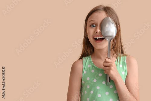Little girl with ladle on beige background