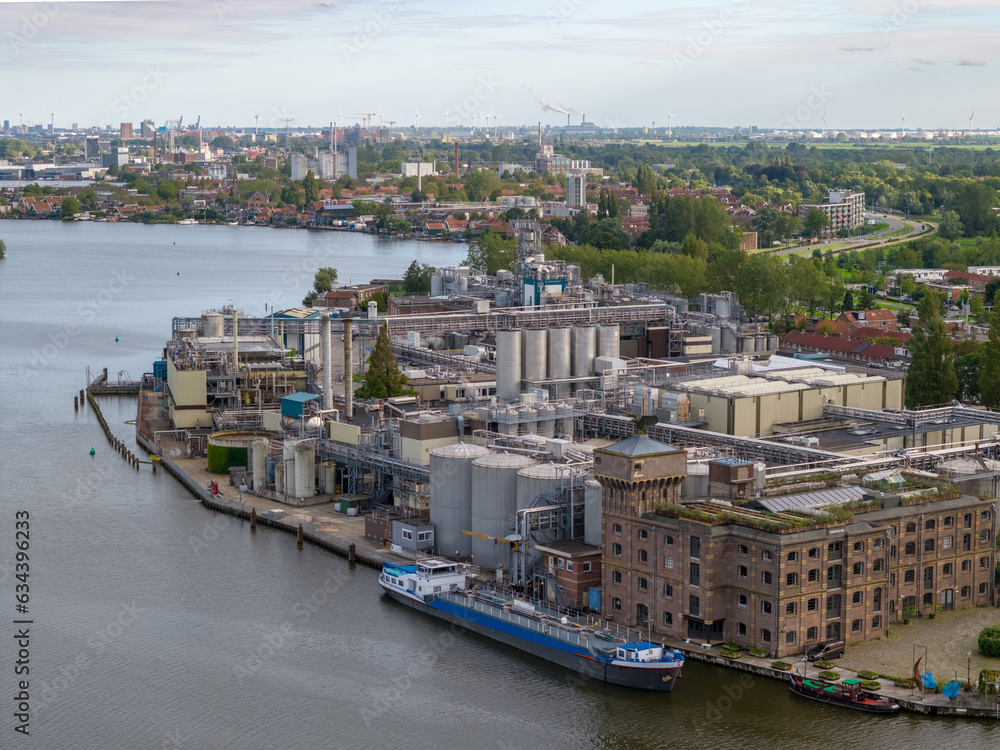 Aerial view of a factory at the river and a cargo barge