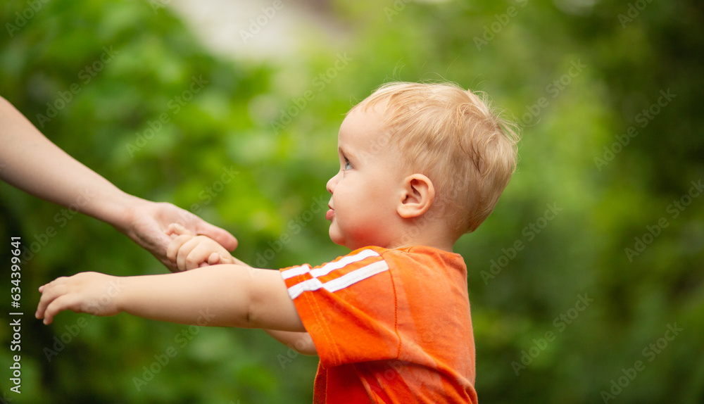 small boy holding mother hand walking in summer park small boy holding mother hand walking in summer park