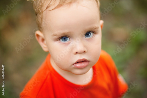 portrait of small blond boy on nature background, baby face
