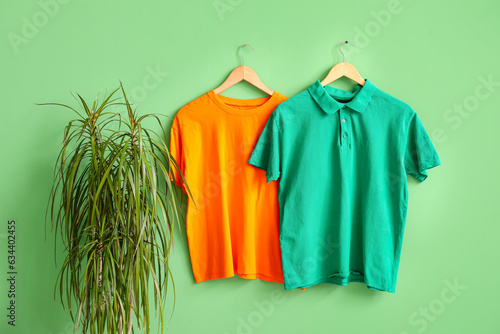 Stylish t-shirts hanging on green background