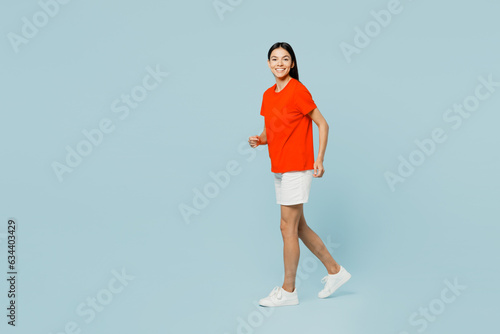 Full body smiling happy cheerful young latin woman wear orange red t-shirt casual clothes hold hands crossed folded look camera isolated on plain pastel light blue cyan background. Lifestyle concept.
