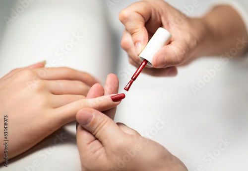 Female Hands While Manicurist Applying Polish On Fingernails Indoor  Closeup