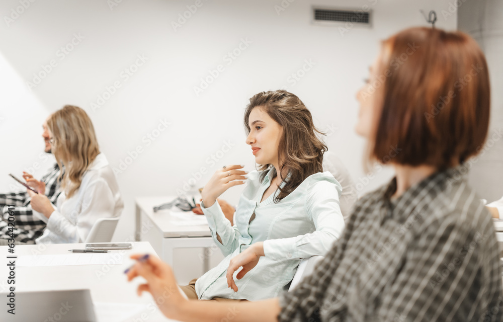 Girl looking at colleagues discussing with slight smile on her face Girl looking at colleagues discussing with slight smile on her face
