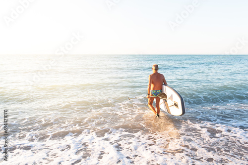 adult entering the sea with a board