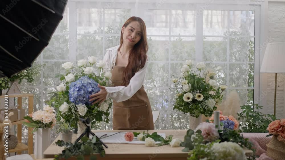 Beauty lady blogger florist and Vlog make content concept.Young florist female routine tutorial at camera on tripod at workplace.Influencer artist woman live streaming in flower shop studio at home. Beauty lady blogger florist and Vlog make content concept.Young florist female routine tutorial at camera on tripod at workplace.Influencer artist woman live streaming in flower shop studio at home.