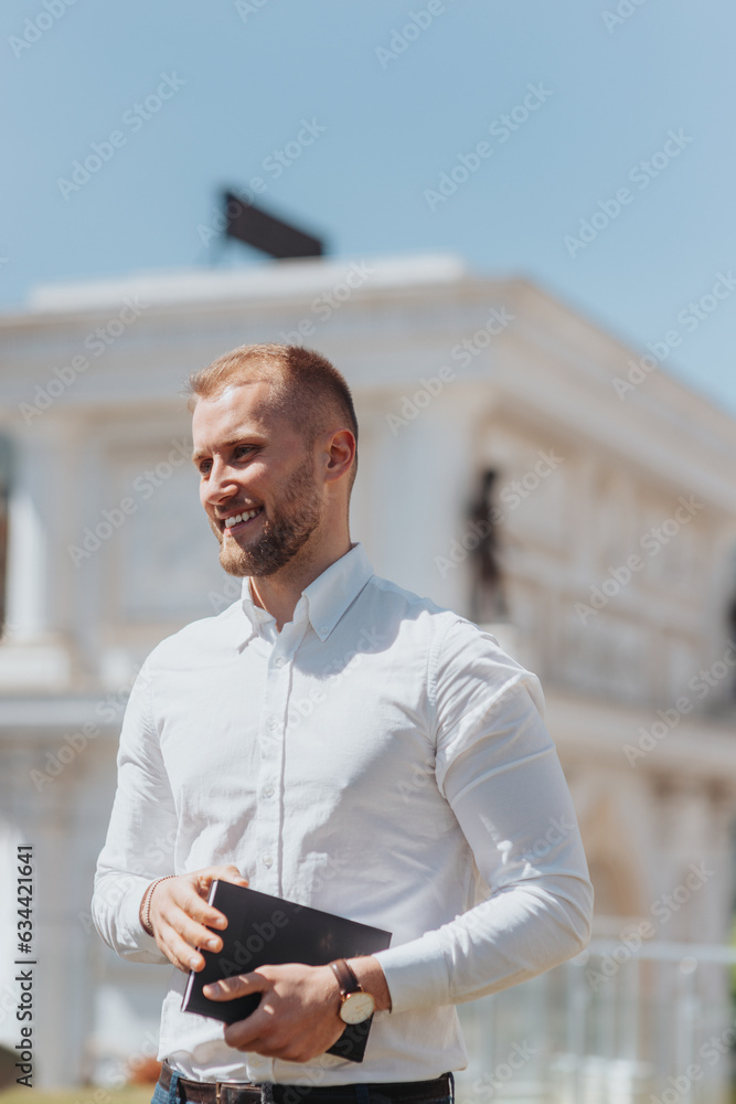 Handsome, smiley businessman holding notebook Handsome, smiley businessman holding notebook