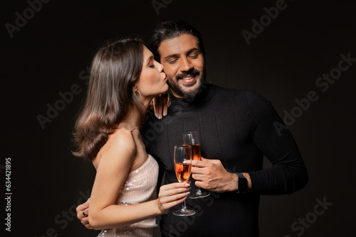 Beautiful woman kissing man, holding glasses of champagne