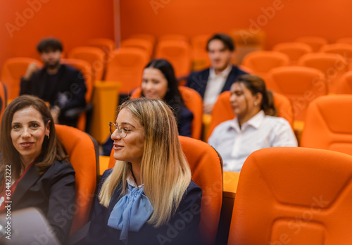 Student smiling and listening to her professor give a lecture