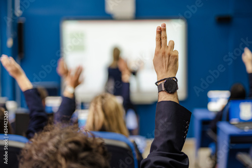 Students raising hands to ask questions during lecture at school