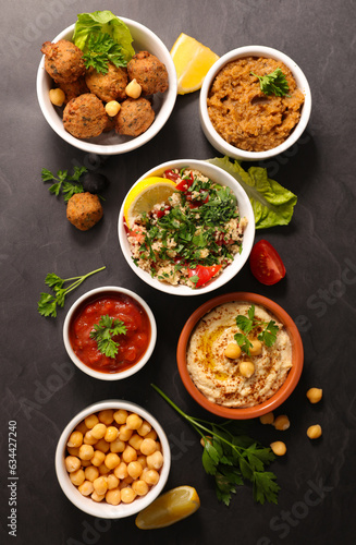 Assorted Middle Eastern and arabic dishes on a dark background- hummus, tabbloueh,salad,falafel