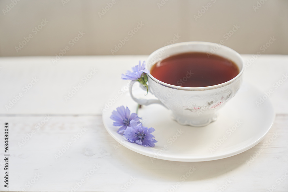 Drink from chicory roots in a cup, flowering cornflower plants on a white wooden table. An alternative to decaffeinated coffee. High quality photo Drink from chicory roots in a cup, flowering cornflower plants on a white wooden table. An alternative to decaffeinated coffee. High quality photo