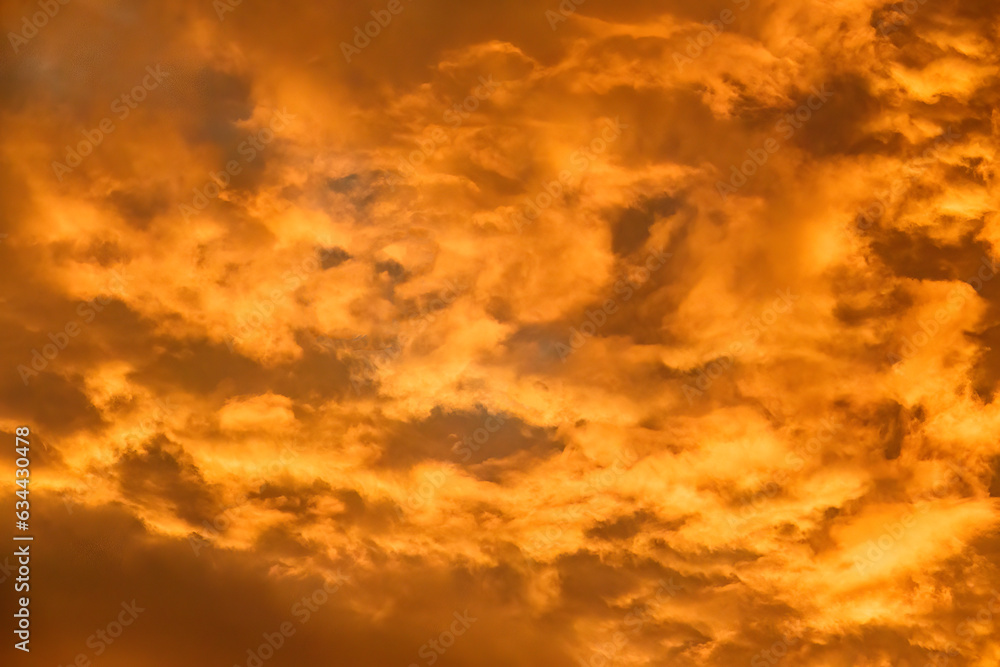Fiery sky, in shades of orange, at sunset or early twilight, for background or element with motifs of summer and heat waves, illumination, transition