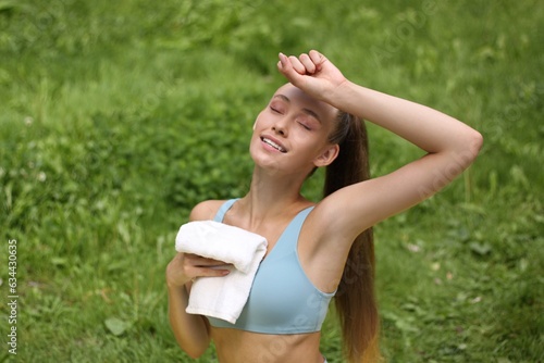 Portrait of pretty young sporty girl resting after sports training. Tired and exhausted. Wiping the sweat with a towel. Wearing stylish sportswear top. Resting after workout.