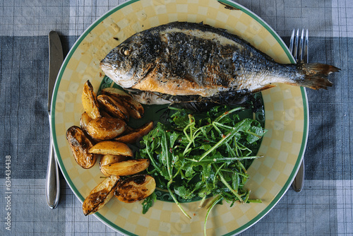 Bild von Dorade Fisch mit Kartoffeln und Rucolasalat, angerichtet auf einem Teller