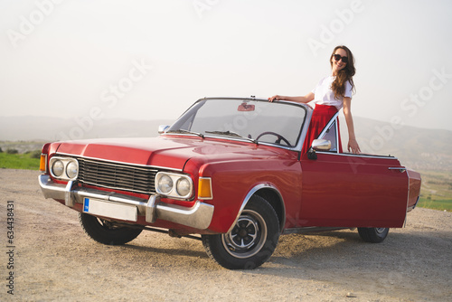 beautiful happy girl in a skirt posing near a retro car in the mountains of cappadocia