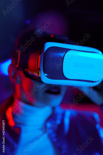 Trendy woman in virtual reality goggles on dark
