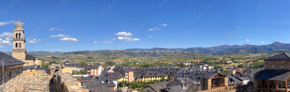 Panoramic high angle view of Ponferrada, Spain, as seen from Templar castle, with church tower,  traditional slate roofs and green hills in the background.