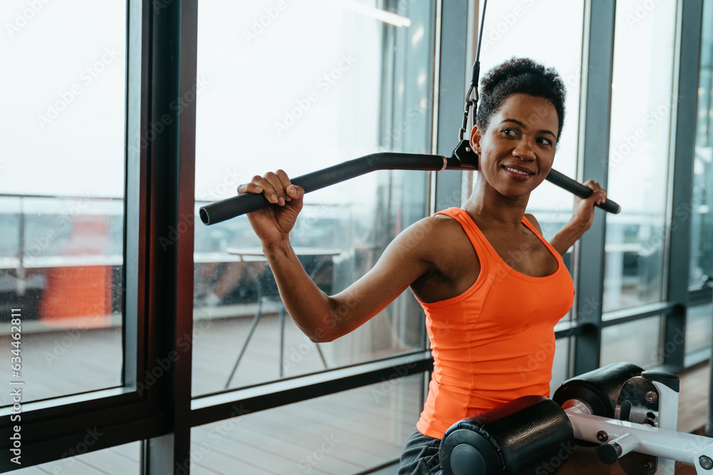 Young happy athlete woman with sweat doing exercises, working out on Lat machine in fitness gym. Strong and healthy concept. Young happy athlete woman with sweat doing exercises, working out on Lat machine in fitness gym. Strong and healthy concept.