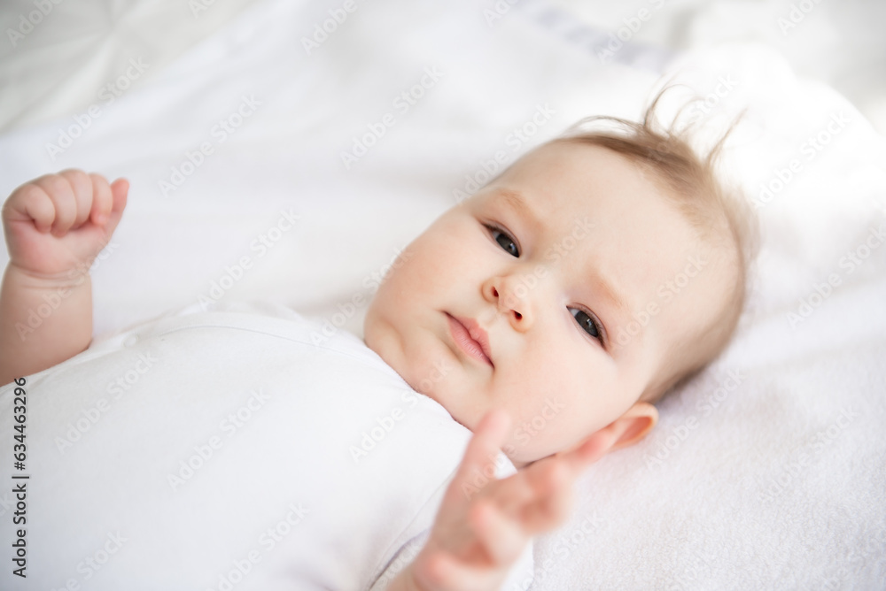Charming baby on a white bed in the bedroom. Charming baby on a white bed in the bedroom.