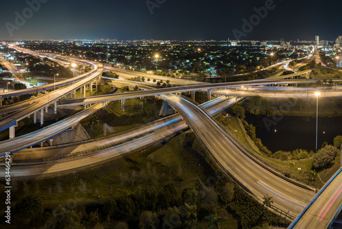 Aerial view of american freeway intersection at night with fast driving cars and trucks in Miami, Florida. View from above of USA transportation infrastructure