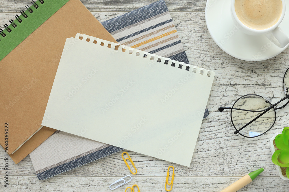 Work desk with notepad, blank notepad, coffee cup and pen on a wooden table. Flat copy space from above. business technology concept. Work desk with notepad, blank notepad, coffee cup and pen on a wooden table. Flat copy space from above. business technology concept.