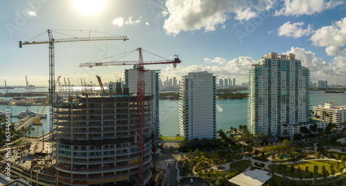 New construction site of developing residense in american urban area. Industrial tower lifting cranes in Miami, Florida. Concept of housing growth in the USA