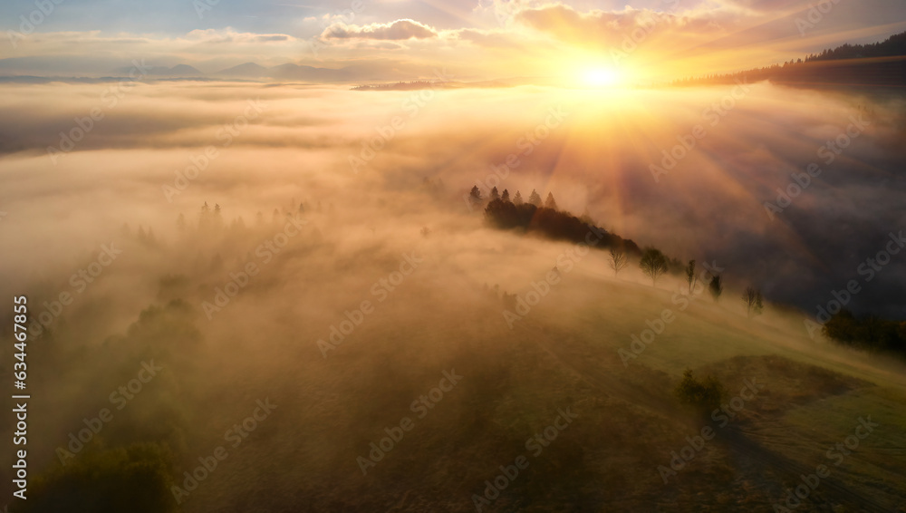 Obraz premium Fog spreads over the mountains at dawn. The sun rises on the horizon. Carpathians in the morning. Aerial drone view.