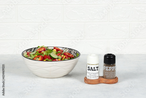 Salt and pepper next to the salad bowl