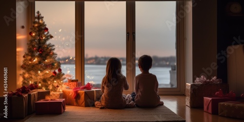 Two kids sitting together and looking to Christmas tree, view from the back