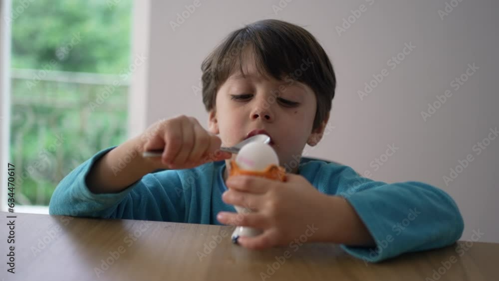 Child breaking soft boiled egg with spoon, preparing to eat oeuf a la coque. Close-up kid hitting the surface of healthy snack Child breaking soft boiled egg with spoon, preparing to eat oeuf a la coque. Close-up kid hitting the surface of healthy snack