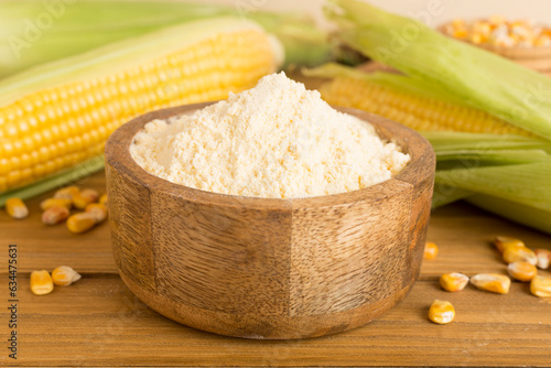 Corn flour with fresh cobs on wooden table