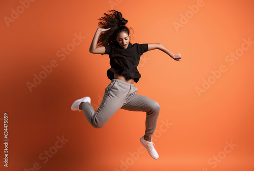 Boundless Joy: A Radiant Brunette Woman Leaping with Delight against a Vibrant Orange Backdrop ai generative