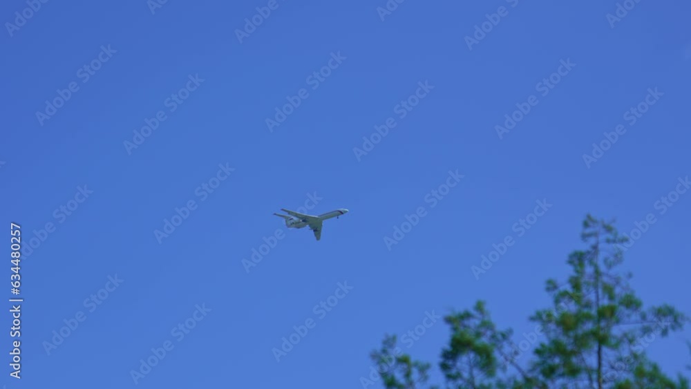 A military plane flies by above in the blue sky. A military plane flies by above in the blue sky.