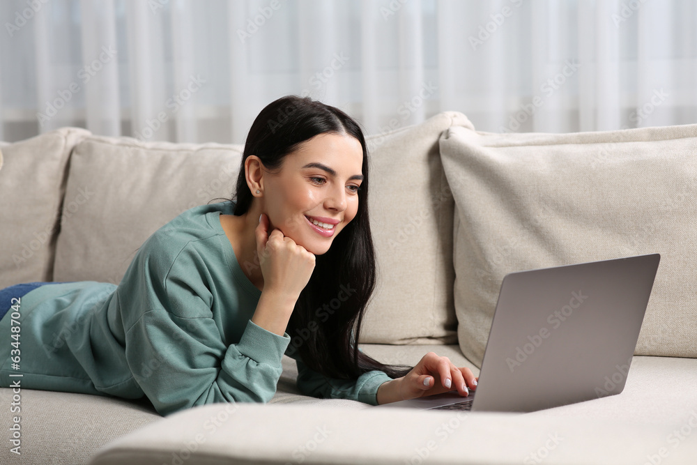 Happy woman working with laptop on sofa at home Happy woman working with laptop on sofa at home