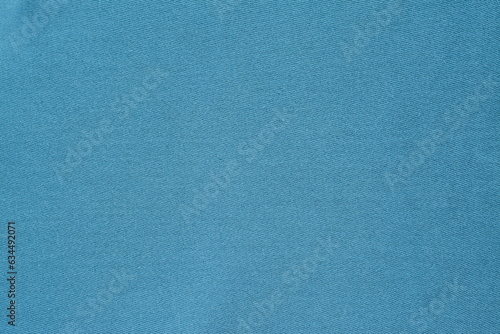 Background of light blue plain jeans in aquamarine shade, top view
