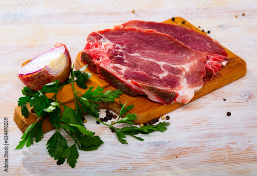 Raw meat, two fresh pork cutlets on wooden cutting board