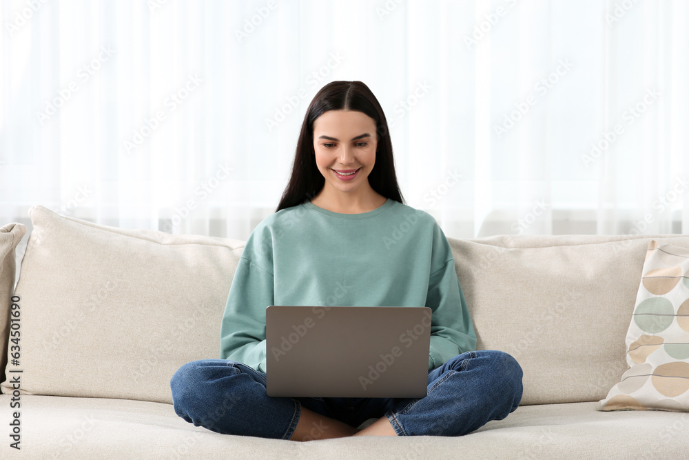 Happy woman working with laptop on sofa at home Happy woman working with laptop on sofa at home