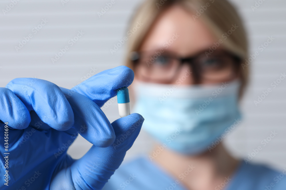 Doctor holding pill on light background, selective focus. Space for text Doctor holding pill on light background, selective focus. Space for text