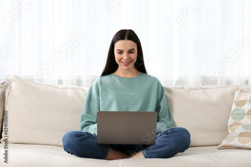 Happy woman working with laptop on sofa at home